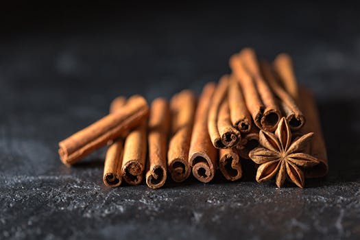 About Close-up of cinnamon sticks and star anise on a dark, textured surface, evoking warm, aromatic flavors.